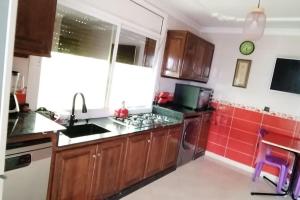 een keuken met houten kasten en rode tegels bij شقة مفروشة للكراء اليومي في الناظور ليلى in Selouane