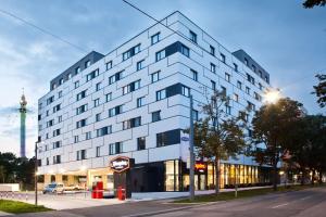 a white building on a street with a tower in the background at Hampton By Hilton Vienna Messe in Vienna