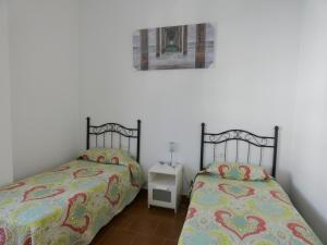 2 Betten nebeneinander in einem Zimmer in der Unterkunft Chalet primera línea, La Barrosa in Chiclana de la Frontera