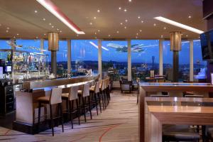 a restaurant with a bar with a view of the city at Hilton Zurich Airport in Opfikon