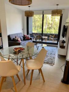 Una sala de estar con una mesa de cristal y sillas. en hermoso departamento 1 dormitorio en entorno natural, en Pucón