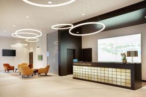 a waiting room with chairs and a presentation on a screen at Hilton Garden Inn Zurich Limmattal in Spreitenbach