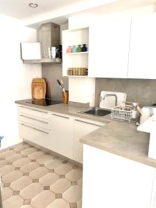 uma cozinha com armários brancos e piso em azulejo em Appartement 3P 88 m2 terrasse et jardin à 20 metres de la plage em Antibes