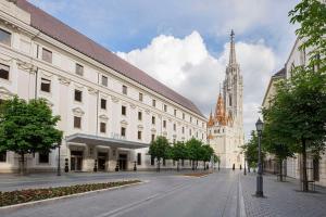 une rue de la ville avec un grand bâtiment et une église dans l'établissement Hilton Budapest, à Budapest