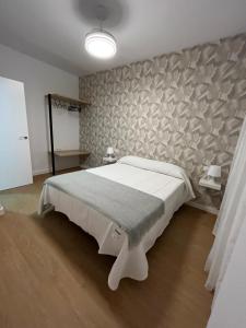 a bedroom with a large white bed and a stone wall at apartamentos Larios centro in Sanlúcar de Barrameda +42 photos