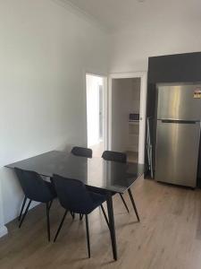 a dining room table with chairs and a stainless steel refrigerator at Milton House, Hamilton in Hamilton