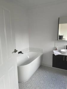 Baño blanco con bañera y lavamanos en Milton House, Hamilton, en Hamilton