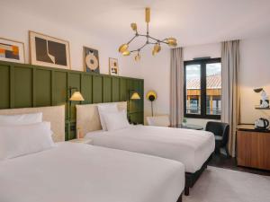 a hotel room with two beds and a desk at Marty Hotel Bordeaux - Tapestry Collection by Hilton in Bordeaux