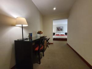 Zimmer mit einem Schreibtisch und einem Schlafzimmer mit einem Bett. in der Unterkunft LP Los Portales Hotel Cusco in Cusco