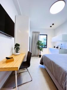 a bedroom with a desk and a bed and a kitchen at White Door Apartments in Haifa