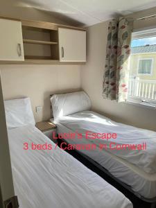 a small bedroom with two beds and a window at Lucie’s Escape/ 129 meadow view in Grampound