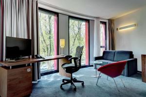 a hotel room with a desk and chairs and a television at Hilton Garden Inn Stuttgart NeckarPark in Stuttgart