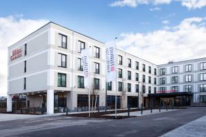 a white building with a street in front of it at Hilton Garden Inn Munich Messe in Feldkirchen