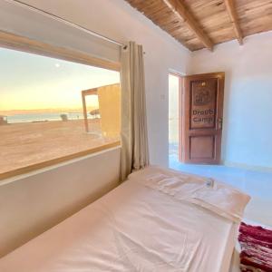 a bed in a room with a window with a view of the beach at New Droub Camp in Nuweiba