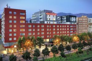 a building in a city with trees and buildings at Hilton Garden Inn Tirana in Tirana