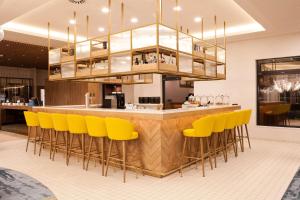 eine Bar in einem Restaurant mit gelben Barhockern in der Unterkunft Hilton Garden Inn Munich Messe in Feldkirchen + 60 Fotos