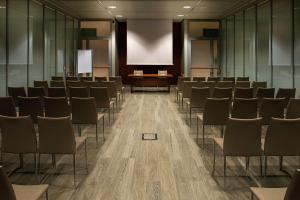 a conference room with chairs and a podium and a screen at DoubleTree by Hilton Turin Lingotto in Turin