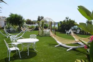a garden with chairs and a table and swings at Grand Hotel Des Sablettes Plage, Curio Collection By Hilton in La Seyne-sur-Mer