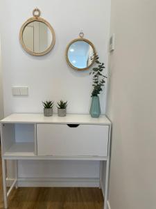 a white dressing table with a mirror and potted plants at Gaudi Street Apartments in Sitges