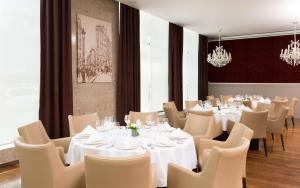 ノヴォシビルスクにあるDoubleTree by Hilton Novosibirskの白いテーブルと椅子、シャンデリアのあるレストラン