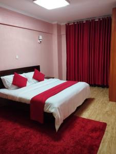 a bedroom with a large bed with red curtains at Beauty Homes Kilimani in Nairobi