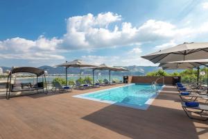 - une piscine avec des chaises et des parasols dans un bâtiment dans l'établissement Hilton Garden Inn Novorossiysk, à Novorossiisk