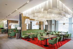 a restaurant with tables and green chairs and a chandelier at Hilton Garden Inn Novorossiysk in Novorossiysk