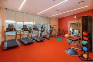een fitnessruimte met cardio-apparatuur in een kamer met oranje muren bij Hilton Garden Inn Novorossiysk in Novorossiejsk