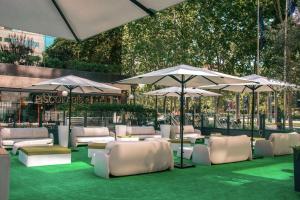 a patio with white chairs and umbrellas on the grass at Hilton Barcelona in Barcelona