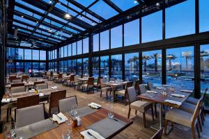 a restaurant with tables and chairs in a room with windows at Hilton Garden Inn Izmir Bayrakli in Izmir