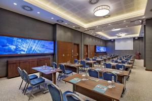 uma sala de conferências com mesas e cadeiras e um ecrã de projecção em Hilton Garden Inn Izmir Bayrakli em Esmirna