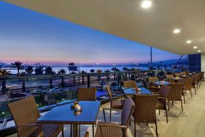 イズミールにあるHilton Garden Inn Izmir Bayrakliのテーブルと椅子が備わり、海の景色を望むレストラン