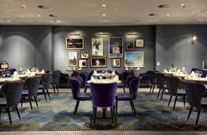 هيلتون دوسلدورف في دوسلدورف: غرفة طعام مع طاولات وكراسي وصور على الجدران