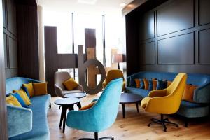 a lobby with blue couches and yellow chairs at Hampton By Hilton Aachen Tivoli in Aachen