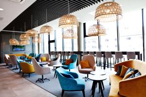 a waiting room with chairs and tables and chandeliers at Hampton By Hilton Aachen Tivoli in Aachen