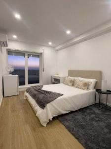 a white bedroom with a large bed and a window at Quarto duplo com casa de banho exclusiva no Porto in Porto