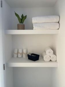 a white shelf with towels and a plant on it at Quarto duplo com casa de banho exclusiva no Porto in Porto