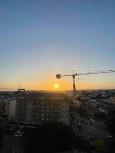 um pôr-do-sol sobre uma cidade com uma grua de construção em Quarto duplo com casa de banho exclusiva no Porto em Porto