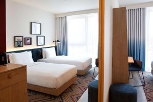 Una habitación de hotel con dos camas y una ventana. en Hampton by Hilton Munich Airport South, en Hallbergmoos 31 fotos más