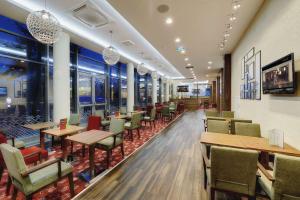 un restaurante con mesas, sillas y ventanas en Hampton by Hilton Volgograd Profsoyuznaya, en Volgograd