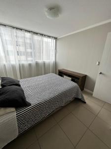 a bedroom with a bed with a black and white blanket at DEPARTAMENTO ARRIENDO DIARIO in La Serena