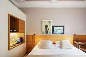 1 dormitorio con cama blanca y cabecero de madera en Alexandra Barcelona Hotel, Curio Collection by Hilton, en Barcelona