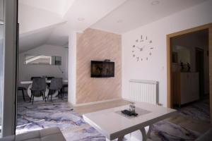 a living room with a table and a clock on a wall at Luxury Apartments Milićević in Trebinje