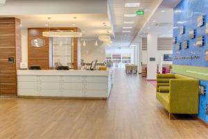an office lobby with a reception desk and a green chair at Hampton by Hilton Ufa in Ufa