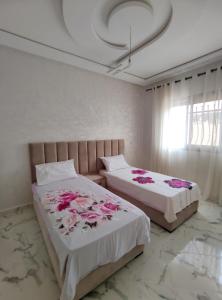 - 2 lits dans une chambre ornée de fleurs roses dans l'établissement Ayour appartement, à Azrou