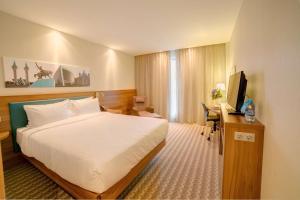 ウファにあるHampton by Hilton Ufaのベッド、デスク、テレビが備わるホテルルームです。