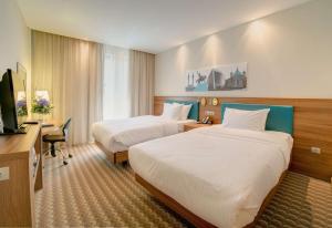 ウファにあるHampton by Hilton Ufaのベッド2台、デスク、テレビが備わるホテルルームです。