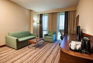 Hilton Garden Inn Erzincan في إرزينجان: غرفة في الفندق تحتوي على أريكة وكراسي وتلفزيون