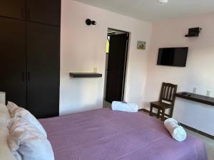 um quarto com uma cama roxa e uma cadeira em LA VILLA DE LA ABUELA em San Cristóbal de Las Casas