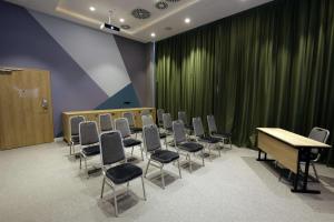 une salle de conférence avec des chaises, une table et un rideau vert dans l'établissement Hampton By Hilton Olsztyn, à Olsztyn